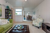 Located at 3601 Clinton Pkwy in Lawrence, Kansas, this single-floor residence offers a well-designed layout with a cohesive flow between living, dining, and kitchen areas. The spacious living room features soaring vaulted ceilings, a ceiling fan, and plush carpeting. Large windows and a glass-panel exterior door flood the room with natural light while providing outdoor views. A pass-through opening connects the living area to the bright, galley-style kitchen, which is appointed with white cabinetry, ample counter space, tile flooring, and a full suite of appliances including a range, microwave, refrigerator, and dishwasher. The adjacent dining area accommodates a full-sized table and is accented by a pendant light fixture. Two bedrooms feature ceiling fans, vaulted or tray ceiling details, and soft carpeting, offering comfortable and restful retreats. The unit includes two full bathrooms, each with tile flooring, white vanity cabinetry, and generous counter space. One bathroom features a shower-tub combo with glass sliding doors, while the other offers a walk-in shower configuration. Neutral tones throughout the residence create a clean, versatile aesthetic suitable for a variety of interior styles.