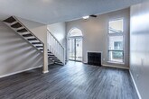 The Cypress floor plan in Memphis, Tennessee offers a well-designed two-story layout with 2 bedrooms and 2 bathrooms. The main level features an open living area with soaring vaulted ceilings, a ceiling fan, a cozy fireplace with tile surround, and a striking arched window that fills the space with natural light. Wood-look flooring runs throughout the main level, complementing the neutral warm tones found throughout the home. The kitchen is accessible via a pass-through opening and is equipped with white cabinetry and modern appliances. A dedicated laundry area with white upper cabinets and granite countertop space adds practical functionality. A staircase with white baluster railing leads to the upper level, where both bedrooms are carpeted and well-lit by windows with blinds. The primary bedroom includes a walk-in closet and a private en-suite bathroom featuring granite countertops, white cabinetry, and a separate shower. The second full bathroom is outfitted with a full tub/shower combination, granite vanity top, and wood-look tile flooring. A hallway on the upper level connects the bedrooms, offering a clean and efficient layout. The overall design is clean, neutral, and move-in ready.