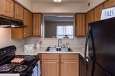 Located at 1421 Cloverdale Cir in Hixson, Tennessee, this single-floor residence offers a practical and comfortable layout throughout. The kitchen is well-appointed with warm wood-toned cabinetry, ample upper and lower storage, light countertops, a double-basin sink beneath a window, and black appliances including an electric range, dishwasher, and refrigerator — all set on durable hardwood-style flooring. A dedicated dining area adjacent to the kitchen features a pendant light fixture and a window that brings in natural light, complemented by plush carpeting. The living room is generously sized with soft carpet, neutral walls, a textured ceiling, and a sliding glass door fitted with vertical blinds that opens to an outdoor area, filling the space with natural light. The carpeted bedrooms are well-proportioned, with one featuring a ceiling fan with light kit and a window with blinds. A carpeted hallway with hardwood-style flooring transitions connects the rooms with closet access along the way. Storage is well-served by a walk-in closet with wire shelving. Both bathrooms are finished with hardwood-style flooring, a vanity with storage, a toilet, and a shower-tub combination. Throughout the home, textured ceilings, neutral tones, and white trim provide a clean, cohesive aesthetic.