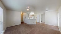 This single-floor residential unit offers a practical and comfortable layout centered around an open-concept living and dining area. The spacious living room is finished with plush wall-to-wall carpeting and features a ceiling fan with integrated lighting. A large window allows natural light to fill the room while providing views of surrounding greenery outdoors. The kitchen is positioned at the heart of the unit, defined by a peninsula counter that separates it from the living area. It is equipped with light wood cabinetry, white appliances including a refrigerator, electric range, over-the-range microwave, and dishwasher, alongside wood-look flooring and ample counter space. The bedrooms are generously sized, each featuring plush carpeting, ceiling fans, and windows that bring in natural light and outdoor views. A standout feature is the walk-in closet, offering substantial storage with wrap-around shelving. The unit includes two full bathrooms, each equipped with a tub-shower combination. One bathroom showcases wood-look flooring and light wood vanity cabinetry with a single sink, while the other is finished with clean white surfaces and wood-look flooring. Throughout, the interiors are finished in neutral tones, creating a bright and cohesive atmosphere.