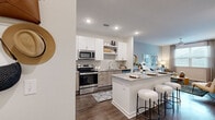 Located at 14350 Ambrosia Street in Tampa, FL, this one-bedroom, one-bathroom residence offers a thoughtfully designed open-concept floor plan with contemporary finishes throughout. The kitchen serves as the centerpiece of the living space, showcasing stainless steel appliances, a dual-tone cabinet design pairing crisp white uppers with warm wood-finish lowers, a subway tile backsplash, open shelving, and a generous granite-topped island with bar seating — ideal for casual dining or entertaining. Wood-style flooring flows seamlessly through the kitchen and into the adjoining living area, which features a ceiling fan and a large window dressed with elegant draping, filling the space with natural light. The primary bedroom is a comfortable retreat with a ceiling fan, a well-sized window, and direct access to a walk-in closet equipped with multi-tiered wire shelving. The bathroom is cleanly appointed with a granite vanity, wood-tone cabinetry, a large mirror with lighted surroundings, and a full tub-shower combination with white tile surround. Wood-style flooring continues throughout, tying the home together with a cohesive, modern aesthetic that is both functional and stylish.
