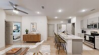 This well-appointed 3-bedroom, 2-bathroom single-story residence offers a thoughtfully designed open-concept layout with a clean, modern aesthetic. Light hardwood flooring flows throughout the space, complementing the bright white walls and recessed lighting that create a fresh, airy atmosphere.

The kitchen serves as a central hub of the home, featuring gray shaker-style cabinetry, granite countertops, and a full suite of stainless steel appliances including a refrigerator, range, and microwave. A spacious kitchen island with seating for multiple guests doubles as a breakfast bar, seamlessly connecting the kitchen to the living and dining areas. An open pantry with built-in shelving adds practical storage. The living room is anchored by a sliding glass door that invites natural light and provides outdoor access.

The primary bedroom is a comfortable retreat, offering ample space and a dedicated walk-in closet with dual hanging rods and built-in shelving. The two bathrooms feature granite vanities and a tub-shower combination. Both additional bedrooms are well-sized and share access to the second full bathroom. The residence combines functional design with contemporary finishes, making it an efficient and stylish living space.