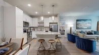Located in Saint Johns, FL, this thoughtfully designed 2-bedroom, 2-bathroom residence offers a comfortable and modern living experience across a single floor. The open-concept kitchen and living area serves as the heart of the home, featuring white shaker cabinets, granite countertops, stainless steel appliances, a tile backsplash, and a central island with bar seating illuminated by stylish pendant lighting. Light wood-look flooring flows throughout the main living areas, connecting the kitchen seamlessly to the bright living room, which is filled with natural light from large windows and features a ceiling fan. The primary bedroom is a generously sized retreat with plush carpeting, direct access to a private en-suite bathroom, and a walk-in closet with built-in shelving. The primary bathroom offers a dual-sink vanity with granite countertops and white cabinetry. The second bedroom is equally well-proportioned with soft carpeting and convenient hallway access to the second full bathroom, which includes a single vanity and a tub-shower combination. A dedicated laundry room with side-by-side washer and dryer hookups and overhead shelving adds everyday convenience. The overall ambiance is clean, modern, and functional throughout.