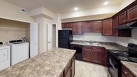 This single-floor residence offers a thoughtfully designed layout with a range of practical features throughout. The kitchen is a standout area, showcasing rich dark-cherry cabinetry, granite-style countertops, and a full suite of black appliances including a gas range, refrigerator, and dishwasher. A generous kitchen island provides additional prep and serving space, while recessed lighting and stone-tile flooring complete the functional yet stylish design. The kitchen connects seamlessly to the rest of the living areas, with doorways leading to additional rooms.

The bedrooms are carpeted and feature warm neutral tones, ceiling fans with integrated lighting, and windows that allow natural light to filter in. One bedroom opens to French doors, offering direct access to an outdoor area and enhancing the sense of openness. The spacious primary bedroom benefits from dual windows, adding to its bright and airy character.

The bathrooms are finished with stone-tile flooring in neutral tones. One bathroom includes a soaking tub alongside a separate shower-tub combination, while another features chrome fixtures and grab bars for added accessibility. The overall ambiance of the space is clean, neutral, and move-in ready, providing a comfortable and versatile living environment.