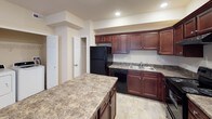 This single-floor residence offers a thoughtfully designed layout with a range of practical features throughout. The kitchen is a standout area, showcasing rich dark-cherry cabinetry, granite-style countertops, and a full suite of black appliances including a gas range, refrigerator, and dishwasher. A generous kitchen island provides additional prep and serving space, while recessed lighting and stone-tile flooring complete the functional yet stylish design. The kitchen connects seamlessly to the rest of the living areas, with doorways leading to additional rooms.

The bedrooms are carpeted and feature warm neutral tones, ceiling fans with integrated lighting, and windows that allow natural light to filter in. One bedroom opens to French doors, offering direct access to an outdoor area and enhancing the sense of openness. The spacious primary bedroom benefits from dual windows, adding to its bright and airy character.

The bathrooms are finished with stone-tile flooring in neutral tones. One bathroom includes a soaking tub alongside a separate shower-tub combination, while another features chrome fixtures and grab bars for added accessibility. The overall ambiance of the space is clean, neutral, and move-in ready, providing a comfortable and versatile living environment.
