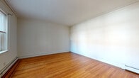 This single-floor residential unit offers a well-organized layout that includes multiple rooms connected by a practical and efficient floor plan. Throughout the living and bedroom areas, warm-toned hardwood flooring adds a classic character, complemented by crisp white walls, crown molding details, and clean white baseboards that give each room a tidy, finished appearance. Natural light filters in through multiple windows fitted with blinds, brightening the interior and creating an inviting atmosphere. Baseboard heating units are present throughout, ensuring consistent warmth. The living and bedroom spaces are generously proportioned, providing ample room for furnishing and personalization. Closet and interior door access points are visible in the bedroom areas, offering practical storage solutions. The kitchen is equipped with rich medium-toned wood cabinetry, granite-style countertops, a gas range, a full-size refrigerator, and a sink — all set on light-toned ceramic tile flooring. A window above the counter area allows natural light into the kitchen. The bathroom is clean and functional, featuring white ceramic tile flooring, a bathtub with shower, a toilet, a vanity with sink, and a window that provides ventilation and daylight. Overall, the unit presents a well-maintained, move-in-ready space with classic design elements and practical amenities throughout.