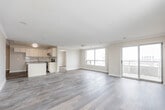 Located at 57 Queen St N in the heart of Kitchener, Ontario, this well-appointed 2-bedroom, 2-bathroom unit offers a thoughtfully designed single-floor layout. Warm hardwood-style flooring flows throughout, complementing a neutral, light colour palette that enhances the bright and airy feel of the space.

The open-concept kitchen is a standout feature, equipped with crisp white shaker cabinetry, grey quartz-style countertops, a subway tile backsplash, stainless steel appliances including a range, microwave, and dishwasher, and a peninsula island ideal for casual dining or meal prep. The kitchen connects seamlessly to the living area, which is generously sized and bathed in natural light through large sliding glass doors leading to a private balcony with open city views.

Both bedrooms are comfortably sized with large windows framing urban views. The primary bedroom includes a dedicated closet with sliding doors. The bathrooms are cleanly finished, with one featuring a full soaker tub surrounded by classic white subway tile and brushed nickel fixtures.

Additional highlights include a dedicated in-unit laundry room with full-sized washer and dryer, a welcoming entrance corridor, and crown moulding details in the living area. The overall ambiance is clean, modern, and move-in ready.