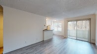 This single-floor unit offers a clean, functional layout designed for comfortable everyday living. The open-concept living and dining area is bright and welcoming, featuring light-toned luxury vinyl plank flooring, a textured ceiling, and large windows that invite natural light and outdoor views. A sliding glass door provides direct access to an outdoor space, further enhancing the airy atmosphere.

The kitchen is efficiently designed and positioned adjacent to the living area, separated by a breakfast bar with a dark speckled countertop. White cabinetry provides ample storage, while appliances include an electric range, over-the-range microwave, refrigerator, and a sink — all finished in white for a cohesive look.

A dedicated entryway with wood-toned flooring greets residents upon arrival, offering a defined transition into the living space. The bedroom features a sliding-door closet with a full-width hanging rod, offering convenient storage. The full bathroom is neatly appointed with a vanity featuring a dark countertop, a toilet, and a bathtub with a shower surround and brushed nickel fixtures.

Throughout the unit, the consistent flooring, neutral color palette, and clean finishes create a cohesive and move-in ready environment.