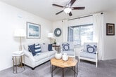 Located at 46 E Point Dr in Draper, Utah, this well-appointed single-floor home offers three bedrooms and two bathrooms across a comfortable, efficiently designed layout. The living room is a welcoming centerpiece, featuring plush carpet, a ceiling fan with light fixture, and large windows with plantation shutters and draped curtains that fill the space with abundant natural light. The adjacent dining area continues the bright, airy feel with multiple windows and neutral tones, creating an inviting setting for meals. The galley-style kitchen is outfitted with white cabinetry, tile flooring, track lighting, a double sink, and a full suite of appliances, offering a clean and functional workspace. The bedrooms are carpeted and well-proportioned, each benefiting from natural light through shuttered windows. The primary bedroom includes closet access and a calming accent wall. Two hallways connect the living spaces to the bedrooms and utility areas, with windows at the ends adding brightness. Both bathrooms feature tile flooring, white vanity cabinetry, and tub-shower combinations, maintaining a consistent, clean aesthetic throughout. The overall ambiance is warm, neutral, and move-in ready.