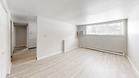 Located at 1136 Vine St in Liverpool, NY, this 3-bedroom, 1-bathroom unit offers a practical and well-organized single-floor layout. Light-toned hardwood flooring runs throughout the entire space, lending a clean, cohesive aesthetic to every room. The neutral gray and white walls provide a bright, airy feel that makes the most of the available square footage.

The generously sized primary bedroom offers notable floor space and features a window that allows natural light to filter in, along with baseboard heating for year-round comfort. The two additional bedrooms are well-proportioned, each with white interior doors and the same consistent flooring found throughout the unit.

The galley-style kitchen is efficiently arranged with white cabinetry lining both sides, a coil electric range, a full-size refrigerator, and a double-basin sink with ample counter space — ideal for everyday cooking needs. The full bathroom includes a shower-tub combination, toilet, and a wood-toned vanity, all finished in clean white surroundings.

A hallway connects the main living areas, and the spacious living area features a window-mounted air conditioning unit, a large window for natural light, and baseboard heating. The primary bedroom also includes a double-door closet, adding practical storage to this well-appointed unit.