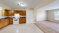 Located at 14827 Porterfield Dr in Orange, Virginia, this single-story home offers three bedrooms and three bathrooms within a well-organized, functional floor plan. The kitchen is equipped with warm oak cabinetry, ample counter space, and white appliances including a range, dishwasher, and refrigerator, with light tile flooring that extends into the adjacent areas. The layout flows naturally from the kitchen toward the carpeted living spaces, creating a cohesive feel throughout the home. The primary bedroom is generously sized, featuring large windows that invite natural light and views of the surrounding greenery, with soft wall-to-wall carpeting underfoot. The two additional bedrooms are comfortably proportioned, each with carpeted floors, neutral walls, and windows providing natural light. The three bathrooms are finished with tile flooring; one features a soaking tub and towel bar, another includes a walk-in shower, and a third offers a vanity with oak cabinetry and a lighted mirror. Consistent warm beige tones and clean white trim throughout the home create a neutral, move-in-ready aesthetic. Paneled interior doors, ceiling-mounted light fixtures, and well-maintained finishes contribute to the home's tidy and practical character.