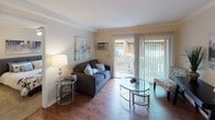 Located at 1501 S Highland Ave in Fullerton, California, this single-floor residence offers a thoughtfully laid-out interior with a functional blend of comfort and practicality. The living room serves as the heart of the home, featuring rich hardwood flooring, crown molding, and a sliding glass door flanked by vertical blinds that opens directly onto a private outdoor patio — allowing natural light to fill the space and providing a seamless indoor-outdoor connection. A wall-mounted air conditioning unit ensures year-round comfort in this area.

The kitchen is efficiently designed with warm honey-toned cabinetry, dark granite-style countertops, and wood-look flooring. It is fully equipped with black appliances including an electric range, over-the-range microwave, and a stainless steel refrigerator, along with a double basin sink — making it a highly functional space for everyday cooking.

The bedroom is a serene retreat finished with plush carpeting, neutral walls, and a ceiling fan with integrated lighting. A window dressed with blinds and decorative curtain panels brings in natural light while maintaining privacy. The bathroom features a clean, full-size shower and tub combination with a classic curtain rod setup, finished in crisp white surroundings.
