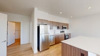 This well-designed single-floor residence offers three bedrooms, two bathrooms, and a thoughtfully arranged layout that maximizes functionality. The open-concept kitchen and living area serves as the heart of the home, featuring a sleek island with light quartz countertops, warm wood-tone cabinetry extending to the ceiling, a full suite of stainless steel appliances including a refrigerator, range, microwave, and dishwasher, and a subway tile backsplash. Recessed lighting and elevated ceiling height in the kitchen area add to the sense of openness.

Light hardwood flooring flows consistently throughout the entire residence, contributing to a clean, cohesive aesthetic. The living area receives abundant natural light through large windows that frame outdoor views of surrounding greenery and water. Each bedroom is well-proportioned, bright, and sun-filled, with windows providing pleasant outdoor views. The primary bedroom is generously sized and comfortably accommodates standard furnishings.

Both bathrooms feature wood-tone vanity cabinetry, light countertops, large mirrors, and matching hardwood-style flooring. A dedicated utility room and closet provide practical storage solutions. The hallways connecting the rooms are clean and well-lit, reinforcing the unit's modern, minimal design throughout.