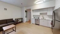 Located at 2024 Durant Ave in Berkeley, California, this two-bedroom, one-bathroom unit offers a thoughtfully designed single-floor layout with a clean, modern aesthetic. Light wood-tone flooring runs throughout, complementing the bright white walls and flush-mount ceiling lighting that keep the space feeling open and airy.

The combined living, dining, and kitchen area forms the heart of the unit. The kitchen is well-appointed with sleek white flat-front cabinetry, stainless steel appliances including a refrigerator, gas range, microwave, and dishwasher, and a double-basin sink with a modern faucet. The open layout allows the kitchen to flow naturally into the living and dining areas, making the space feel connected and functional.

A dedicated laundry area with a stacked washer and dryer is conveniently tucked off the main living space. A hallway leads to both bedrooms and the shared bathroom. The primary bedroom is a comfortable size, featuring a ceiling fan with light, a window for natural light, and ample room for furnishings. The second bedroom is more compact and well-suited as a study or sleeping space, with its own door for privacy. The bathroom includes a full tub-shower combination with tiled surround, brushed nickel grab bars, and light wood flooring.