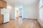 Located at 511 W Doty St in the heart of Madison, Wisconsin, this efficiently designed single-floor unit offers a practical and cohesive layout. Warm hardwood flooring runs throughout the space, lending a consistent and inviting aesthetic to every room.

The main living area is open and functional, featuring a ceiling fan and an integrated kitchenette along one wall. The kitchenette is equipped with warm wood cabinetry, a white range, sink, and refrigerator, complemented by a tile backsplash. The layout allows the kitchen and living areas to share a unified, open feel.

A separate room off the main living area provides added versatility and benefits from natural light streaming in through a large double-pane window fitted with blinds, offering views of surrounding greenery. A baseboard heating unit runs beneath the window, ensuring warmth during Wisconsin's colder months. This room also features a mirrored sliding closet door, adding both storage and a sense of depth.

The bathroom is finished with classic light-green ceramic tile surrounding the tub and shower combination, paired with chrome fixtures and a wood-framed door. The neutral wall tones throughout the unit, combined with the hardwood floors, create a clean and cohesive interior environment well-suited for comfortable everyday living.