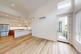Located at 2611 First St in Napa, CA, this thoughtfully designed 2-bedroom, 2-bathroom home offers a clean, contemporary aesthetic throughout. The open-concept living and dining area immediately impresses with soaring ceilings and a dramatic wall of windows, including clerestory windows that flood the space with natural light. Light wood-tone flooring runs throughout the main living areas, complementing the bright white walls. A wall-mounted mini-split system provides efficient climate control. A sliding glass door leads to a private balcony, extending the living space outdoors.

The kitchen is a standout feature, boasting a peninsula with pendant lighting, crisp white upper cabinetry, warm wood-toned lower drawers, white quartz countertops, and a full suite of stainless steel appliances. A pantry provides additional storage. The adjacent dining area flows seamlessly from the kitchen.

Both bedrooms are carpeted and bathed in natural light through large windows with outdoor views. The primary bedroom is generously sized and includes a dedicated closet. The two bathrooms are finished with wood-toned vanities and light wood flooring — one features a walk-in glass shower, the other a full tub-shower combo. An in-unit laundry area adds everyday convenience.