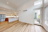 Located at 2611 First St in Napa, CA, this thoughtfully designed 2-bedroom, 2-bathroom home offers a clean, contemporary aesthetic throughout. The open-concept living and dining area immediately impresses with soaring ceilings and a dramatic wall of windows, including clerestory windows that flood the space with natural light. Light wood-tone flooring runs throughout the main living areas, complementing the bright white walls. A wall-mounted mini-split system provides efficient climate control. A sliding glass door leads to a private balcony, extending the living space outdoors.

The kitchen is a standout feature, boasting a peninsula with pendant lighting, crisp white upper cabinetry, warm wood-toned lower drawers, white quartz countertops, and a full suite of stainless steel appliances. A pantry provides additional storage. The adjacent dining area flows seamlessly from the kitchen.

Both bedrooms are carpeted and bathed in natural light through large windows with outdoor views. The primary bedroom is generously sized and includes a dedicated closet. The two bathrooms are finished with wood-toned vanities and light wood flooring — one features a walk-in glass shower, the other a full tub-shower combo. An in-unit laundry area adds everyday convenience.