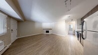 Located at 4701 E Mississippi Ave in Glendale, Colorado, this 1-bedroom, 1-bathroom unit offers a well-organized layout across a single floor. The open-concept living area is anchored by a distinctive corner fireplace with a white tile surround and wood mantel, creating a warm focal point. Wood-look vinyl plank flooring extends throughout the living and kitchen areas, lending a clean and cohesive aesthetic. The kitchen is equipped with stainless steel appliances, including a range and refrigerator, complemented by dark espresso cabinetry and a tile backsplash. Track lighting provides practical illumination throughout the main living space. The bedroom features plush wall-to-wall carpeting, a ceiling fan with light fixture, and a standout whitewashed exposed brick accent wall that adds character and texture. A window with blinds allows natural light to filter in. The bedroom offers generous storage with double sliding closet doors providing ample wardrobe space. A baseboard heating system ensures year-round comfort. The unit's neutral color palette throughout creates a versatile backdrop suited to a variety of personal styles.