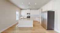 Located at 990 Perth Rd in Mooresville, NC, this two-story home offers a clean, modern aesthetic throughout its thoughtfully designed layout. The main level features light hardwood flooring that flows through the primary living and dining areas. The dining room stands out with elegant wainscoting panels, a chandelier, and a bright window that fills the space with natural light. The kitchen is well-equipped with white shaker-style cabinetry, granite countertops, a central island, subway tile backsplash, stainless steel appliances, and recessed lighting. A wall of large windows and a glass door in the living area invites abundant natural light and provides outdoor access. The upper level includes carpeted bedrooms, each featuring walk-in closets outfitted with wire shelving systems for ample storage. The primary bathroom offers a double-sink vanity with granite countertops, white cabinetry, and a private water closet. A secondary full bathroom mirrors the same refined finishes, featuring a tub-shower combination and a single granite-topped vanity. Throughout the home, neutral tones, white trim, and consistent finishes create a cohesive and inviting atmosphere.
