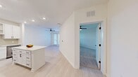 Unit 312 at 900 E Sligh Ave in Tampa, Florida presents a thoughtfully designed one-bedroom, two-bathroom residence that maximizes its efficient single-floor layout. The kitchen serves as a standout feature, showcasing white shaker cabinetry with black hardware, quartz countertops, a subway tile backsplash, and a full suite of stainless steel appliances. A generous island provides additional prep and dining space, while light wood-look flooring runs throughout the main living areas, complementing the bright, neutral color palette. The open living area benefits from natural light through large windows with outdoor views of surrounding greenery, and is outfitted with a ceiling fan. The spacious primary bedroom features plush carpeting, a ceiling fan, and a well-sized walk-in closet with multi-tiered wire shelving for organized storage. Both bathrooms reflect a clean, modern aesthetic with white vanities, quartz surfaces, black-framed mirrors, and matte black fixtures. The second bathroom includes a frameless glass walk-in shower with marble-style tile surround and a sleek black door handle. Overall, the unit delivers a cohesive, contemporary feel throughout.