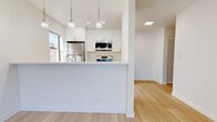 Located at 3761 Harrison St in Oakland's vibrant Temescal-adjacent neighborhood, this single-floor unit offers a clean, contemporary design with a cohesive neutral palette throughout. Light wood flooring extends seamlessly across all living areas, creating a warm and unified aesthetic.

The kitchen is a standout feature, appointed with crisp white shaker cabinetry, quartz countertops, and a full suite of stainless steel appliances including a gas range, built-in microwave, and refrigerator. A peninsula with pendant lighting above defines the kitchen space and provides an open connection to the living area, which benefits from natural light and a spacious, airy feel.

The bathroom is finished with a white shaker-style vanity, quartz countertop, brushed nickel hardware, and a marble-tiled shower-tub combination enclosed by a glass sliding door, lending a polished, spa-like quality to the space.

The bedrooms are bright and well-proportioned, with one featuring a mirrored sliding closet and another offering a window with views of the surrounding Oakland streetscape. Wall-mounted heating units and programmable thermostats ensure year-round comfort. Throughout, the crisp white walls and clean lines contribute to a modern, move-in-ready atmosphere ideal for urban living.