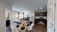 This single-story residence in Gonzales, Louisiana offers a thoughtfully designed open-concept layout connecting the main living areas. An entry hallway adorned with gallery-style wall art leads into the combined dining, living, and kitchen space. The kitchen is equipped with stainless steel appliances, dark espresso cabinetry, granite countertops, a subway tile backsplash, and pendant lighting above the peninsula, which provides additional prep and dining space. The adjacent dining area accommodates a full table, while the living room features dark hardwood-style flooring, a ceiling fan, and windows that allow natural light to fill the space. Both bedrooms are carpeted and include ceiling fans and windows with outdoor views. The primary bedroom features a walk-in closet, while the en-suite bathroom offers a granite-topped vanity with dark cabinetry and a soaking tub with shower. The second bathroom mirrors the design with matching finishes and hardwood-style flooring. A framed mirror, dark vanity cabinetry, and consistent granite countertops carry the cohesive aesthetic throughout the home.