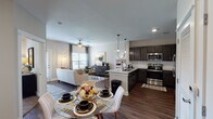 This single-story residence in Gonzales, Louisiana offers a thoughtfully designed open-concept layout connecting the main living areas. An entry hallway adorned with gallery-style wall art leads into the combined dining, living, and kitchen space. The kitchen is equipped with stainless steel appliances, dark espresso cabinetry, granite countertops, a subway tile backsplash, and pendant lighting above the peninsula, which provides additional prep and dining space. The adjacent dining area accommodates a full table, while the living room features dark hardwood-style flooring, a ceiling fan, and windows that allow natural light to fill the space. Both bedrooms are carpeted and include ceiling fans and windows with outdoor views. The primary bedroom features a walk-in closet, while the en-suite bathroom offers a granite-topped vanity with dark cabinetry and a soaking tub with shower. The second bathroom mirrors the design with matching finishes and hardwood-style flooring. A framed mirror, dark vanity cabinetry, and consistent granite countertops carry the cohesive aesthetic throughout the home.
