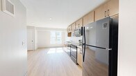 Located at 556 W Lake St in Minneapolis, this 2-bedroom, 1-bathroom unit offers a thoughtfully designed layout with modern finishes throughout. Light wood-toned luxury vinyl flooring runs continuously across the entire space, creating a cohesive and clean aesthetic.

The open-concept kitchen and living area form the heart of the unit. The kitchen features warm maple-toned cabinetry with matte black hardware, white countertops, a double-basin sink, and a full suite of black stainless steel appliances including a refrigerator, electric range, over-the-range microwave, and dishwasher. Ample upper and lower cabinet storage maximizes functionality. The adjacent living area benefits from a large window that brings in generous natural light.

Both bedrooms are well-proportioned with neutral-toned walls, light wood flooring, and closet access. The primary bedroom includes a window with outdoor views, allowing natural light to fill the room.

The full bathroom is finished with large-format light tile flooring, a tub/shower combination with white tile surround, a toilet, and a wood-toned vanity with white countertop and matte black hardware, complemented by a mirror above.

The overall design is clean and contemporary, with a neutral palette that creates a bright, functional living environment.