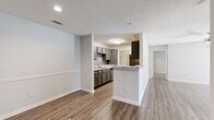 This single-floor residence offers a functional and modern layout across two bedrooms and two full bathrooms. The open-concept living room and kitchen area forms the heart of the home, where warm wood-look LVP flooring, neutral painted walls, and a ceiling fan create an inviting atmosphere. The kitchen is designed for efficiency, featuring a galley-style configuration with gray cabinetry, granite-look countertops, a stainless steel sink, black appliances including an electric range and refrigerator, and a tile backsplash. A peninsula with a breakfast bar connects the kitchen to the living space, adding versatility for dining and entertaining.

Both bedrooms are carpeted and receive natural light through large windows fitted with horizontal blinds. Each room includes a ceiling fan and access to a dedicated closet, with the primary bedroom featuring a spacious walk-in closet equipped with wire shelving. The two full bathrooms are identically appointed with gray vanities, granite-look countertops, and tiled tub-shower combinations with chrome fixtures and wood-look flooring.

A dedicated laundry room accommodates a full-size washer and dryer, adding everyday convenience. Throughout the residence, consistent finishes and a neutral color palette create a cohesive, move-in-ready environment.