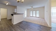 Located at 101 Jousting Ct in Fredericksburg, Virginia, this single-floor residence offers a well-designed, open layout that balances comfort and functionality. The living area is generously sized, featuring plush neutral carpeting and a ceiling fan with integrated lighting. It flows seamlessly into the dining and kitchen area, where wood-look plank flooring adds warmth and continuity throughout the common spaces. A set of French doors in the living room floods the space with natural light and provides access to the outdoors, enhancing the airy feel of the interior.

The kitchen is equipped with white shaker-style cabinetry, dark granite-style countertops, and black appliances including a range, refrigerator, and dishwasher. A breakfast bar peninsula connects the kitchen to the adjoining dining area, which is accented by a stylish chandelier overhead.

The bedroom is carpeted and offers a walk-in closet, providing ample storage. The bathroom features wood-look vinyl flooring, white cabinetry with dark countertops, a tiled tub-shower combination, and a towel bar, presenting a clean and classic aesthetic. Throughout the home, neutral wall tones and consistent finishes create a cohesive and inviting atmosphere.