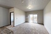 Located at 701 15th St SE in Orange City, Iowa, this two-bedroom, one-bathroom unit offers a practical and comfortable single-floor layout. The open living area is carpeted and bathed in natural light from a sliding glass door that leads to a private balcony with outdoor views, creating a bright and airy atmosphere. A wall-mounted AC unit serves the living space, and a textured ceiling adds character throughout.

The kitchen is well-appointed with rich dark wood cabinetry, light granite-style countertops, wood-look vinyl flooring, and a full suite of black appliances including a range, over-the-range microwave, dishwasher, and refrigerator. The adjacent dining area flows naturally from the kitchen.

Both bedrooms are carpeted and feature natural light from windows with views of the surrounding neighborhood, along with baseboard heating. Ample storage is provided by four closets distributed throughout the unit.

The bathroom includes a full tub-shower combo with clean white surroundings, wood-look flooring, a dark vanity with granite-style countertop, and a toilet. A dedicated laundry area accommodates a stacked washer and dryer unit. A hallway connects the rooms cohesively, completing this functional and well-organized living space.