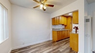 Located at 12618 Lakewood Blvd in Downey, CA, this efficiently designed 2-bedroom, 1-bathroom single-floor unit makes smart use of its compact footprint. Wood-look flooring flows consistently throughout the space, lending a cohesive and modern feel to every room.

The combined living and dining area greets you at entry, featuring ceiling fans with light fixtures and multiple windows dressed with vertical blinds that allow natural light to filter in. The space is open and clean, with crisp white walls and a neutral palette throughout.

The kitchen is well-appointed with warm honey-toned wood cabinetry, granite-look countertops, and a built-in sink. A pantry provides additional storage, keeping the kitchen organized and functional.

The primary bedroom offers a ceiling fan, mirrored sliding closet doors, and light wood flooring, creating a bright and practical retreat. The second bedroom is similarly finished with light wood flooring and a window, offering a clean, versatile space.

The bathroom is neatly appointed with a pedestal sink, full-size soaking tub, and floor-to-ceiling beige tile surrounding the tub/shower combo, complemented by wood-look flooring. A medicine cabinet mirror completes the space. Overall, this unit presents a well-maintained and functional layout suited for efficient everyday living.