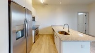 This single-floor unit offers a clean, contemporary design with light wood-style flooring that runs consistently throughout the main living spaces, creating a cohesive and airy feel. The open-concept layout connects the kitchen and living area seamlessly. The kitchen is well-appointed with stainless steel appliances, including a French door refrigerator, electric range, and built-in microwave. White cabinetry extends to the ceiling for ample storage, while granite countertops and a peninsula with an undermount sink provide both workspace and a casual dining option.

The living area is generously sized, filled with natural light from large windows and a glass door that opens to the outdoors. Two bedrooms feature light-toned flooring, ceiling fans with light fixtures, and multiple windows offering outdoor views and natural light. One bedroom includes access to a spacious walk-in closet outfitted with white wire shelving systems for organized storage.

Both bathrooms share a consistent design aesthetic, featuring tile flooring, white floating vanities with granite countertops, and soaking tub and shower combinations with brushed metal fixtures. The overall ambiance is bright, clean, and move-in ready.