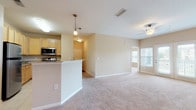 Located in Gallatin, TN, this single-floor residence offers a well-designed, open-concept layout that seamlessly connects the living and kitchen areas. The spacious living room features plush carpeting, a ceiling fan, and access to a private balcony through double glass doors, allowing natural light to fill the space. The kitchen is equipped with stainless steel appliances, including a range and over-the-range microwave, complemented by light wood cabinetry, granite countertops, and tile flooring. A peninsula with pendant lighting provides additional prep space and serves as a natural divider between the kitchen and living areas. Track lighting adds a modern touch to the open living zone. The bedrooms are generously sized, each featuring soft carpeting, ceiling fans, and windows that invite natural light and outdoor views. The bathrooms are appointed with granite-topped vanities, light wood cabinetry, and tile flooring, with the primary bathroom offering a double-sink vanity and a separate shower. A dedicated laundry room with hardwood flooring houses a full-size washer and dryer. Throughout, warm neutral tones and consistent finishes create a cohesive and welcoming ambiance.
