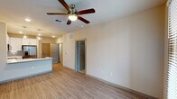 This single-story, one-bedroom, one-bathroom residence in Houston, TX offers a thoughtfully designed open-concept layout finished with consistent wood-look flooring throughout the main living areas. The living room is spacious and bright, anchored by a ceiling fan with light fixture and illuminated by recessed lighting. French doors along one wall invite natural light and provide access to the outdoors, enhancing the airy ambiance of the space.

The kitchen flows seamlessly from the living area and features white shaker-style cabinetry, a tile mosaic backsplash, gleaming quartz countertops, and a large undermount sink set into a kitchen island with pendant lighting overhead. Stainless steel appliances, including a French door refrigerator, electric range, and over-the-range microwave, complete the modern kitchen.

A dedicated laundry closet houses a top-load washer and offers additional storage above. The bedroom is carpeted for comfort, features dual windows for natural light, and connects directly to the full bathroom. The bathroom includes a white vanity, a tiled tub/shower combination, and access to a well-organized walk-in closet with built-in shelving and hanging rods.