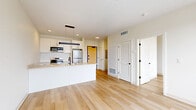 Located at 2132 Stokes Blvd in Cleveland's vibrant University Circle area, this efficiently designed one-bedroom, one-bathroom residence offers a clean, contemporary aesthetic throughout. Light-toned hardwood flooring runs continuously across the entire unit, lending warmth and visual cohesion to every room.

The open-concept kitchen and living area serves as the heart of the home. The kitchen is outfitted with sleek white cabinetry, a white subway tile backsplash, stainless steel appliances including a refrigerator, range, and microwave, and a large peninsula with a quartz countertop and an undermount sink featuring a matte black faucet. A modern linear pendant light anchors the space above.

The bedroom is a bright, well-proportioned retreat with large floor-to-ceiling windows that frame sweeping views of the Cleveland skyline and surrounding neighborhood. Two closets provide ample storage. The bathroom features a frameless glass walk-in shower, contemporary matte black fixtures, and a clean vanity with neutral countertops.

Additional conveniences include an in-unit laundry area. The overall design is defined by crisp white walls, abundant natural light, and a minimalist modern finish palette that creates a fresh, move-in-ready environment.