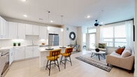 Located at 4830 N Shepherd Dr in Houston, Texas, this single-story unit presents a clean, contemporary design throughout. The open-concept living and kitchen area serves as the heart of the space, where light wood-style flooring, recessed lighting, and large windows create a bright, airy atmosphere. A ceiling fan anchors the living room, which benefits from direct outdoor access through a glass door, allowing natural light to fill the space.

The kitchen is thoughtfully designed with crisp white shaker cabinetry extending to the ceiling, a white quartz countertop island with bar seating for two, a white subway tile backsplash, and a full suite of stainless steel appliances including a refrigerator, range, microwave, and dishwasher. A built-in desk area adjacent to the kitchen adds functional workspace.

The bedrooms are serene and well-lit, each featuring light flooring, ceiling fans or ample natural light through large windows with blinds, and neutral walls that contribute to a calm, restful environment.

The bathrooms maintain the home's clean aesthetic with white cabinetry, quartz vanity surfaces, tile flooring, and bright mirrors. One bathroom features a spacious dual-sink vanity, while another offers a tub-shower combination with white subway tile surround.