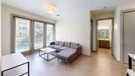 Located at 101 E Abram St in Arlington, TX, this thoughtfully designed unit offers four bedrooms and four bathrooms across a single floor. The open living area features light wood-style flooring, large sliding glass doors that flood the space with natural light, and direct access to a private balcony overlooking a lushly landscaped courtyard with a resort-style pool below. The kitchen is outfitted with stainless steel appliances — including a refrigerator, range, and microwave — complemented by dark wood cabinetry, a subway tile backsplash, and a sleek dining counter with pendant lighting. Each bedroom features plush carpet flooring, built-in storage, and neutral tones that create a calm, functional environment. Select bedrooms benefit from large windows with outdoor views and ceiling fans. All four bathrooms are finished consistently with light wood-style tile flooring, dark wood vanities topped with granite-style countertops, framed mirrors, and tub-shower combinations. A connecting hallway links all rooms efficiently. The unit's clean, contemporary aesthetic is carried throughout, making it a practical and comfortable multi-occupancy residence in the heart of Arlington.