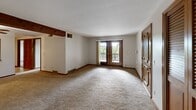 Located on Everhard Road NW in Canton, Ohio, this 2-bedroom, 1-bathroom unit offers a practical and comfortable single-floor layout. The living room is open and generously sized, featuring plush carpeting, warm wood-trimmed accents, an exposed ceiling beam with a ceiling fan, and French doors that lead out to a private balcony with outdoor views — filling the space with natural light.

The kitchen is well-appointed with rich wood cabinetry, a mosaic tile backsplash, light-toned countertops, and a full suite of stainless steel appliances including a refrigerator, range, and dishwasher. A pass-through window connects the kitchen to the adjacent area, enhancing the functional flow of the space.

The primary bedroom is notably spacious, featuring soft carpeting and an impressive dual set of wood-panel sliding closet doors providing abundant storage. The second bedroom also features carpeting, a window with natural light, and its own sliding closet. The full bathroom includes a tub-shower combination, wood-toned vanity cabinetry, a framed mirror, and tile flooring. Warm wood trim and neutral tones carry throughout the unit, lending a cohesive and understated aesthetic.