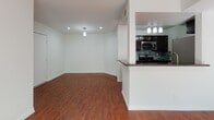 This single-floor residence offers a cohesive and functional layout highlighted by warm hardwood flooring that extends throughout every room. The open-concept design seamlessly connects the kitchen and living area, creating a spacious and inviting atmosphere. The kitchen is well-equipped with stainless steel appliances, including a gas range, over-the-range microwave, and refrigerator, all complemented by dark espresso cabinetry, granite-style dark countertops, and a striking mosaic tile backsplash. A peninsula with decorative column detailing provides additional prep space and serves as a natural divider between the kitchen and the living area. Recessed lighting and pendant fixtures illuminate both spaces effectively. The living area benefits from a large window dressed with sheer curtains, allowing generous natural light to pour in. The bedroom features a ceiling fan, a sliding glass door that opens to an exterior area, and additional window access for cross ventilation. The bathroom is clean and functional, offering a full tub-shower combination, a white vanity, and brushed nickel hardware accents. Overall, the space presents a bright, neutral palette with modern finishes that create a practical yet comfortable living environment.