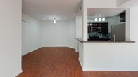 This single-floor residence offers a cohesive and functional layout highlighted by warm hardwood flooring that extends throughout every room. The open-concept design seamlessly connects the kitchen and living area, creating a spacious and inviting atmosphere. The kitchen is well-equipped with stainless steel appliances, including a gas range, over-the-range microwave, and refrigerator, all complemented by dark espresso cabinetry, granite-style dark countertops, and a striking mosaic tile backsplash. A peninsula with decorative column detailing provides additional prep space and serves as a natural divider between the kitchen and the living area. Recessed lighting and pendant fixtures illuminate both spaces effectively. The living area benefits from a large window dressed with sheer curtains, allowing generous natural light to pour in. The bedroom features a ceiling fan, a sliding glass door that opens to an exterior area, and additional window access for cross ventilation. The bathroom is clean and functional, offering a full tub-shower combination, a white vanity, and brushed nickel hardware accents. Overall, the space presents a bright, neutral palette with modern finishes that create a practical yet comfortable living environment.