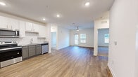 This single-floor residence presents a clean, contemporary design throughout its well-organized layout. The open-concept living and kitchen area serves as the heart of the unit, where durable wood-look flooring flows seamlessly underfoot. The kitchen is equipped with stainless steel appliances, including a refrigerator, range, microwave, and dishwasher, complemented by two-tone gray and white cabinetry, granite-style countertops, and a classic white subway tile backsplash. A ceiling fan overhead and multiple windows allow natural light to fill the connected living space.

The bedrooms feature soft wall-to-wall carpeting and neutral white walls, with ceiling fans and windows providing comfort and natural light. The primary bedroom connects to a full bathroom appointed with a dual-sink vanity, granite countertops, wood-look flooring, and a soaking tub with a tiled surround. A dedicated walk-in closet with wire shelving and carpet flooring offers generous storage.

A separate laundry room houses a full-size washer and dryer on wood-look flooring with additional wire shelving above. Throughout, the unit maintains a bright, neutral palette that creates a clean and functional living environment.