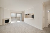 This single-floor, 2-bedroom, 1-bathroom home offers a thoughtfully designed layout that maximizes comfort and functionality. The open-concept living and dining area is a standout feature, anchored by a stone-surround fireplace and complemented by soft carpeting and crown molding throughout. Sliding glass doors lead to a private balcony, filling the space with natural light and providing a seamless indoor-outdoor connection.

The kitchen is efficiently laid out with white cabinetry, light wood-style flooring, a stainless steel range, a black refrigerator, and a peninsula that opens toward the living area — ideal for everyday convenience.

Both bedrooms are carpeted and feature ceiling fans and mirrored sliding closet doors that enhance the sense of space. The primary bedroom includes built-in shelving within the closet, offering generous storage. The second bedroom benefits from a window with natural light.

The bathroom is clean and functional, finished with wood-style tile flooring, a white vanity, and a full shower-tub combination with a small window for ventilation. A hallway connects the main living spaces to the private areas, creating a logical and practical floor plan throughout.