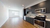 Located at 2315 Valdez St in Oakland's vibrant urban core, this modern single-floor unit offers a thoughtfully designed layout with contemporary finishes throughout. The open-concept living and kitchen area is anchored by warm wood-tone flooring and recessed lighting, creating a bright and welcoming atmosphere. Large windows allow generous natural light to fill the space while offering views of the surrounding cityscape.

The kitchen is a standout feature, outfitted with sleek dark charcoal cabinetry that extends to the ceiling for ample storage, crisp white countertops, and a subtle penny-tile backsplash. A full suite of stainless steel appliances — including a gas range, microwave, dishwasher, and refrigerator — completes the space with a polished, functional aesthetic.

The bedroom is carpeted for comfort, with a large window framing urban views and providing excellent natural light. A second room features matching wood-tone flooring and access to the exterior, offering flexibility as a living or dining area.

The bathroom is finished with classic white subway-style tiles in the tub/shower surround, wood-framed mirror, dark vanity cabinetry with a white countertop, and matching wood-tone flooring, tying together the cohesive design language found throughout the unit.