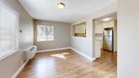 Located at 1865 Lacassie Ave in Walnut Creek, CA, this 2-bedroom, 1-bathroom residence offers a practical and well-designed single-floor layout. The combined living and dining area is bright and open, featuring warm wood-look flooring, neutral taupe walls, and windows that invite natural light and tree-lined views. A pass-through opening connects this space seamlessly to the kitchen, which is well-appointed with white shaker cabinetry, white quartz countertops, and a full suite of stainless steel appliances including a gas range, microwave, dishwasher, and refrigerator. The hallway leads to two carpeted bedrooms, each finished in soft neutral tones. The primary bedroom offers a sliding double closet, providing ample storage. The second bedroom also includes a closet and easy access to the main living area. The shared bathroom features a tub-shower combination, a dark-finished vanity with a white countertop, and wood-look flooring that ties into the rest of the home. Additional conveniences include an in-unit laundry area and wall-mounted HVAC units in the main living space. The overall design is clean, cohesive, and move-in ready.