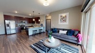 This single-floor residence is thoughtfully designed with a modern aesthetic and quality finishes throughout. The open-concept kitchen and living area serves as the heart of the home, where rich dark cabinetry, granite countertops, and a full suite of stainless steel appliances—including a refrigerator with water dispenser, range, microwave, and dishwasher—anchor the kitchen. A peninsula with seating provides a casual dining option, complemented by stylish pendant lighting overhead. Wood-look flooring flows throughout the main living space, adding warmth and continuity.

The living area is bright and inviting, with a sliding glass door offering outdoor views and generous natural light. A dedicated flex room with large windows and plush carpeting provides an ideal space for a home office or sitting area.

The bedroom is carpeted and comfortably sized, featuring a ceiling fan and direct access to a walk-in closet. The en-suite bathroom showcases granite countertops, dark wood cabinetry, and tile flooring. A second full bathroom with matching granite finishes serves the remainder of the unit. Neutral wall tones and consistent trim details give the entire space a cohesive, polished feel.