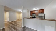 Located on Lexington Pkwy S in Saint Paul, MN, this two-bedroom, two-bathroom residence offers a well-designed single-floor layout that balances comfort and functionality. The open-concept kitchen and living area serves as the heart of the home, featuring warm medium-toned wood cabinetry, stainless steel appliances including a refrigerator, range, and microwave, and a peninsula-style counter that connects the kitchen to the living space. The living room is bright and welcoming, highlighted by sliding glass doors that open to a private balcony overlooking lush greenery, bringing natural light and outdoor views into the space. Durable luxury vinyl plank flooring runs throughout the main living areas, offering a clean, modern aesthetic, while plush carpet adds warmth to both bedrooms. The primary bedroom is generously sized and includes dedicated closet space. The second bedroom offers comparable comfort. Both bathrooms are functional, with one featuring an accessible tub and shower combination equipped with grab bars. A central hallway connects the rooms efficiently, complemented by five closets throughout for ample storage. Textured ceilings, neutral wall tones, and baseboard heating complete the practical and cohesive interior of this Saint Paul residence.