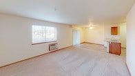 Located at 901 Sunburst Ct, Unit K103 in Moses Lake, Washington, this single-floor residence offers a practical and comfortable layout designed for everyday living. The open living area is generously sized, finished with neutral carpet flooring and neutral-toned walls that create a bright, welcoming atmosphere. A large window allows natural light to fill the space, and a wall-mounted air conditioning unit provides climate control. A ceiling fan with integrated lighting adds to the comfort of the adjoining area, which connects seamlessly via vertical blinds. The kitchen features warm wood cabinetry, light countertops, and a full suite of black appliances including a refrigerator, electric range, and over-the-range microwave, all set over durable wood-look flooring. The two bedrooms are carpeted and well-lit, each equipped with a ceiling fan and windows with blinds. One bedroom includes a mirrored sliding-door closet, while the other benefits from baseboard heating. The bathroom is finished with rich wood cabinetry, a wide vanity with a large mirror, bright overhead lighting, and a walk-in shower. Baseboard heaters throughout provide consistent warmth during cooler months, and the overall design maintains a clean, functional aesthetic throughout.