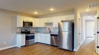 This two-floor home offers a thoughtfully designed layout with a clean, modern aesthetic throughout. The kitchen serves as a functional centerpiece, featuring white shaker-style cabinetry with dark hardware, granite-look countertops, and a full suite of stainless steel appliances including a refrigerator, electric range, over-the-range microwave, and dishwasher. A dark-finish pull-down faucet and a deep sink complete the workspace, while warm wood-look luxury vinyl plank flooring ties the kitchen and adjoining hallway together seamlessly. Recessed lighting illuminates the space efficiently.

The bedrooms are carpeted in neutral tones and finished with soft gray walls, each room benefiting from natural light through slatted window blinds and comfortable airflow provided by ceiling fans. The rooms offer generous proportions, making them adaptable for a variety of uses.

The bathrooms are finished with coordinating granite-look countertops on white vanities and dark oil-rubbed bronze fixtures and hardware, maintaining design consistency throughout the home. One full bathroom includes a tub-shower combination with a built-in shelf unit. A half bath provides added convenience. Overall, the home presents a cohesive, move-in-ready interior with practical finishes and a calm, neutral color palette.