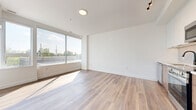Located at 1600 James Naismith Dr in Ottawa, Ontario, this well-designed one-bedroom, one-bathroom unit offers a thoughtfully laid-out floor plan across a single level. Light-toned hardwood-style flooring runs throughout, lending warmth and continuity to the space.

The open living area is bright and airy, benefiting from large floor-to-ceiling windows that flood the interior with natural light and offer pleasant views of the surrounding greenery. The kitchen is neatly integrated into the main living space, featuring white upper cabinetry, wood-toned lower cabinets, a subway tile backsplash, and a full suite of stainless steel appliances including a refrigerator, stove, microwave, and dishwasher. Track lighting above the kitchen adds focused illumination.

A clean hallway connects the living area to the private quarters, which include a comfortable bedroom with its own large windows overlooking trees and outdoor scenery, as well as an adjoining closet for storage. The bathroom is finished with crisp white vertical subway tile surrounding a soaker tub, hexagonal floor tile, and matte black fixtures, creating a modern yet timeless aesthetic. Bright white walls throughout the unit contribute to an overall clean, contemporary ambiance.
